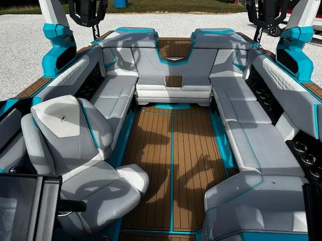 Slide: The Image of 2022 Nautique S23 boat interior with sleek gray and blue seating and wood flooring. - 13
