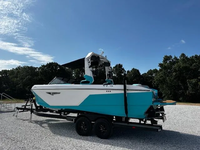 Slide: The Image of 2022 Nautique S23 boat on trailer, turquoise and white, parked outdoors. - 2