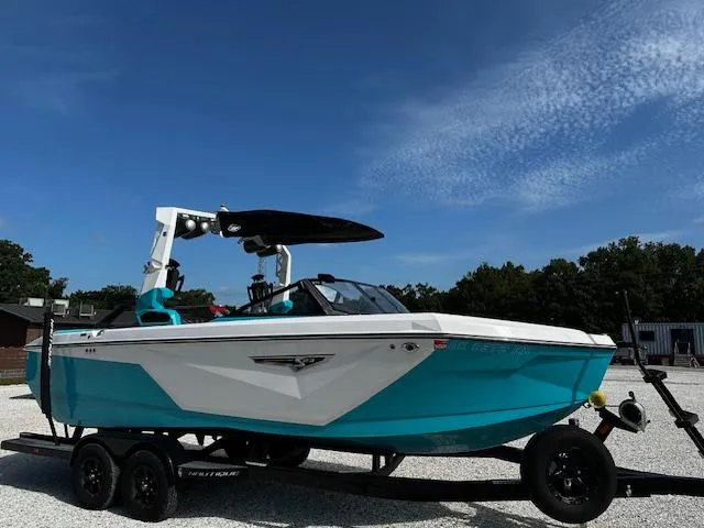 Slide: The Image of 2022 Nautique S23 boat on trailer, vibrant blue and white design, parked outdoors. - 3