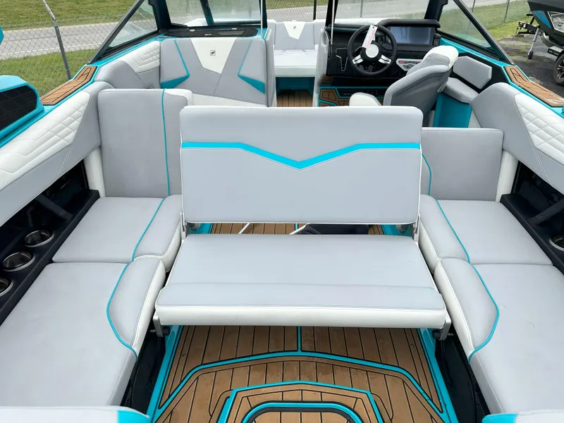 Slide: The Image of 2022 Nautique S23 boat interior with gray and teal seating, wood flooring, and modern dashboard. - 6