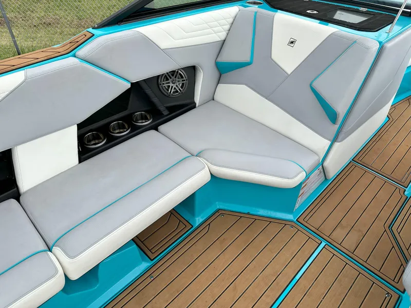 Slide: The Image of 2022 Nautique S23 boat interior with gray and white seating, teal accents, and teak flooring. - 7
