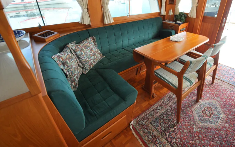 Slide: The Image of Interior of 2000 Grand Banks Heritage Europa 52 with green sofa and wooden dining table. - 42