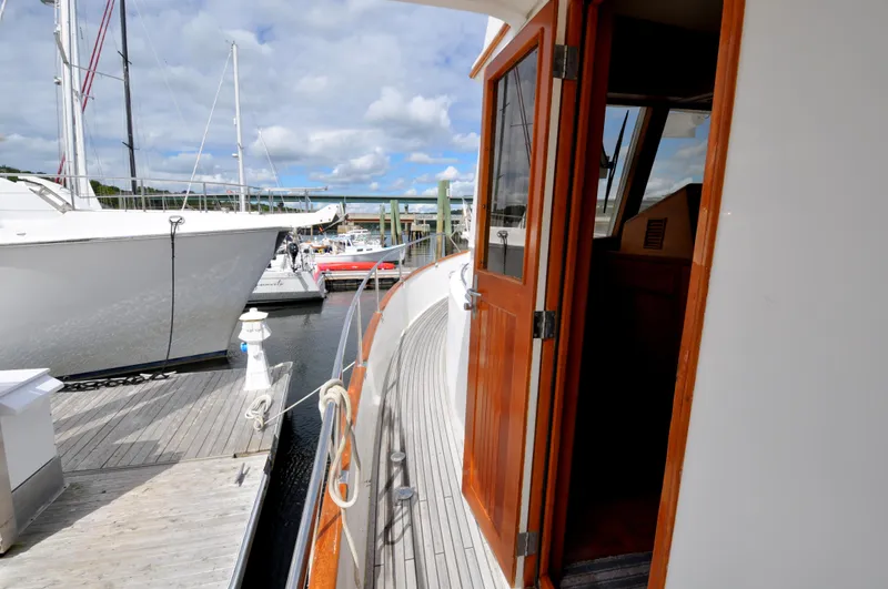 Slide: The Image of 2000 Grand Banks Heritage Europa 52 yacht docked at marina, open cabin door, wooden deck. - 10