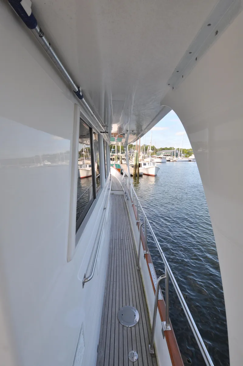 Slide: The Image of Side deck view of 2000 Grand Banks Heritage Europa 52 yacht in marina. - 6