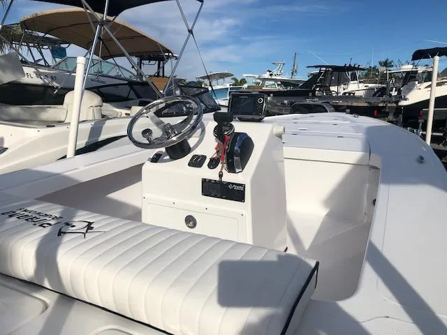 Slide: The Image of 2025 Piranha Alvo F1700 boat interior with steering wheel and seating, docked under clear sky. - 7