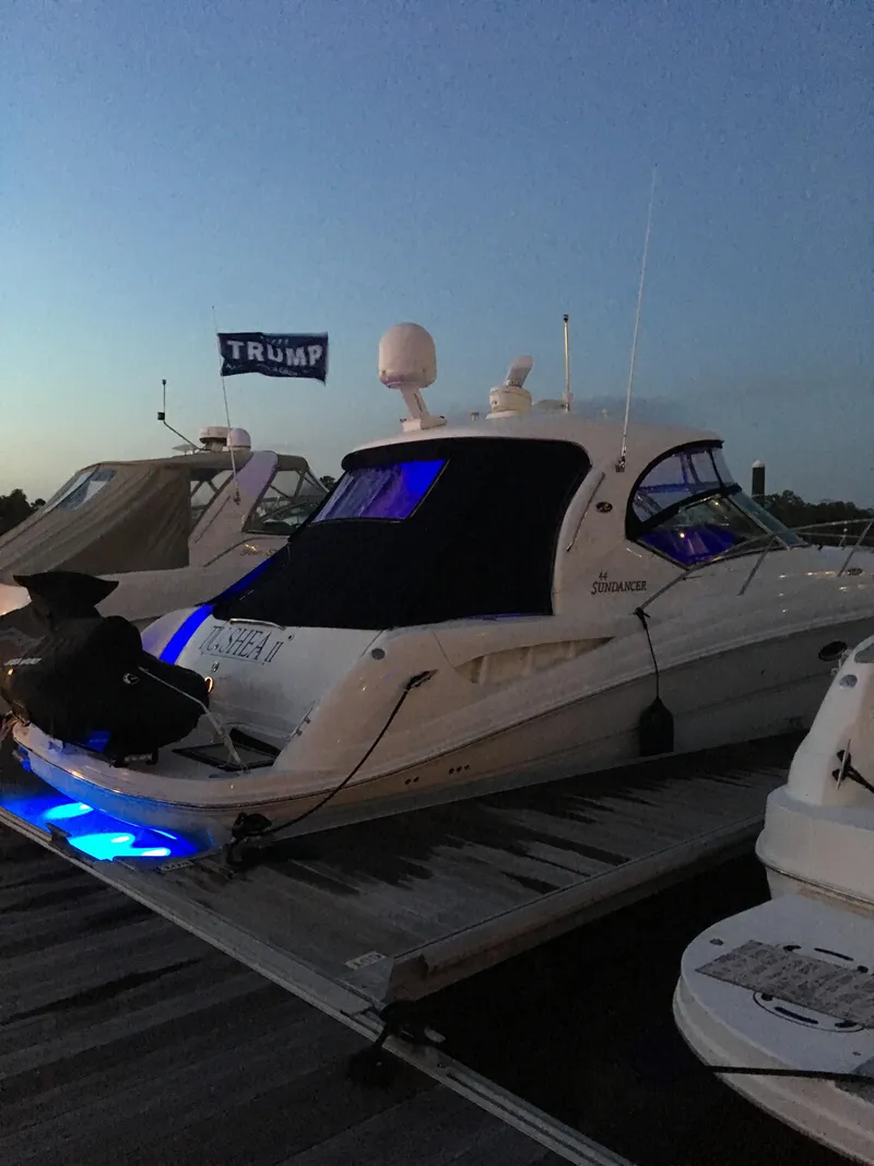 Slide: The Image of 2006 Sea Ray 44 Sundancer yacht docked with blue lights and Trump flag. - 9