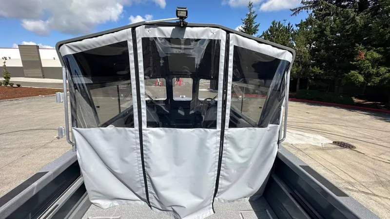 Slide: The Image of 2025 Spartan 215 Athens boat with covered cockpit, parked outdoors under a partly cloudy sky. - 8