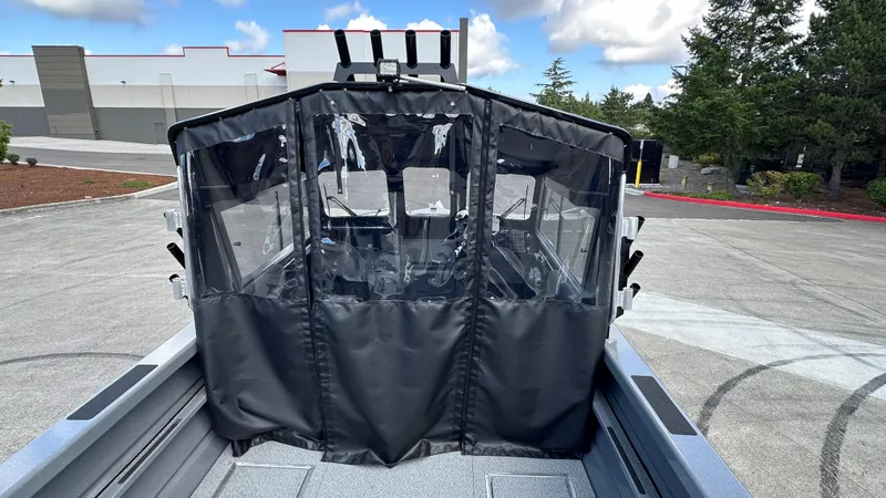 Slide: The Image of 2024 Spartan 200 Astoria boat with protective cover, parked outdoors on a sunny day. - 2