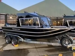 Slide: The Image of 2024 Spartan 200 Astoria boat on trailer, sleek black design, parked outdoors. - 36