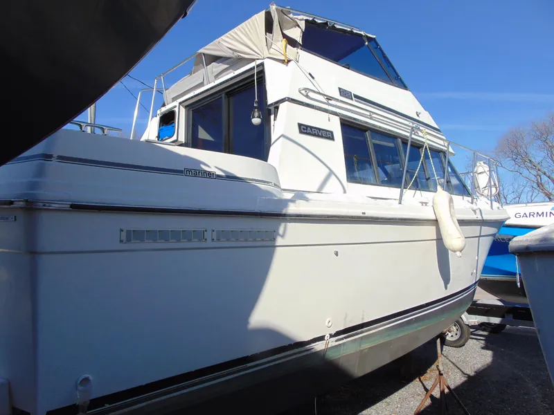 Slide: The Image of 1987 Carver Mariner 28 boat with white exterior, docked under clear blue sky. - 4