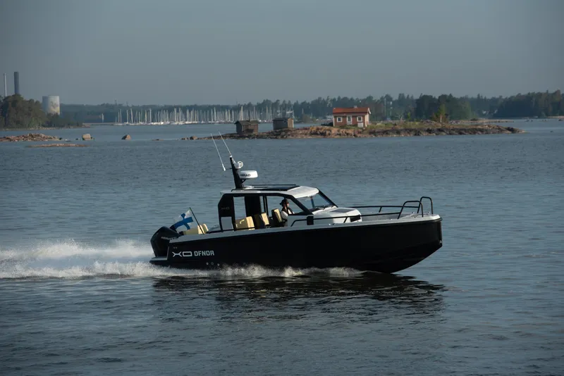 Slide: The Image of 2023 XO Boats Defender 9 cruising on a calm lake with scenic background. - 11