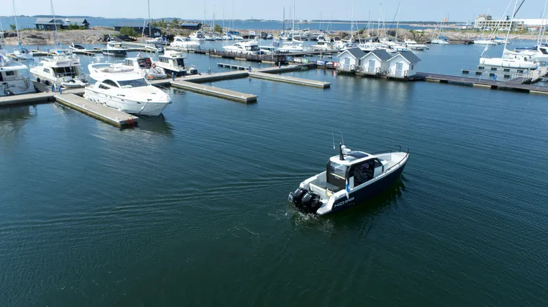 Slide: The Image of 2023 XO Boats Defender 9 cruising in a marina with yachts and docks. - 5