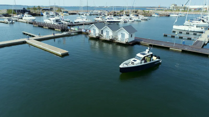 Slide: The Image of 2023 XO Boats Defender 9 in a marina with yachts and small houses. - 6