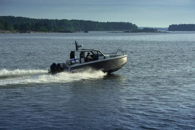 Slide: The Image of 2023 XO Boats Defender 9 cruising on a serene lake. - 7