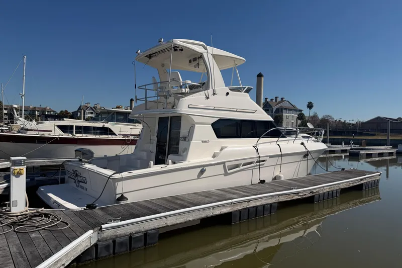 The Image of 2001 Silverton 42 Convertible yacht docked at marina under clear blue sky. - 0