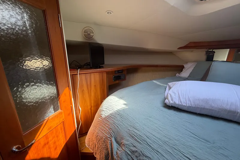 Slide: The Image of 2001 Silverton 42 Convertible yacht bedroom with cozy bed and wooden interior. - 64
