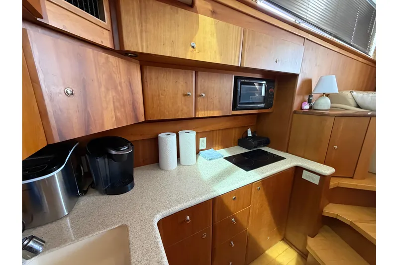 Slide: The Image of 2001 Silverton 42 Convertible yacht kitchen with wooden cabinets, microwave, and appliances. - 90
