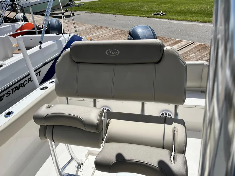 Slide: The Image of 2026 Key West 219 FS boat seat with gray upholstery, docked near other boats. - 8