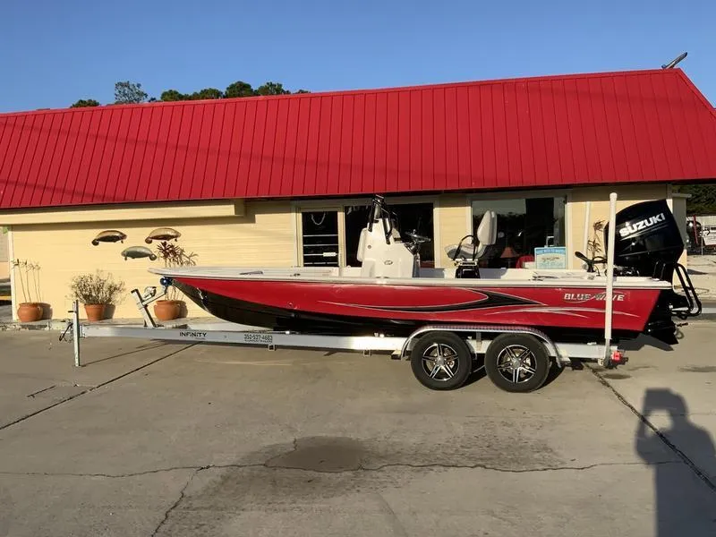The Image of 2022 Blue Wave 2200 STL boat on trailer outside a building with a red roof. - 0