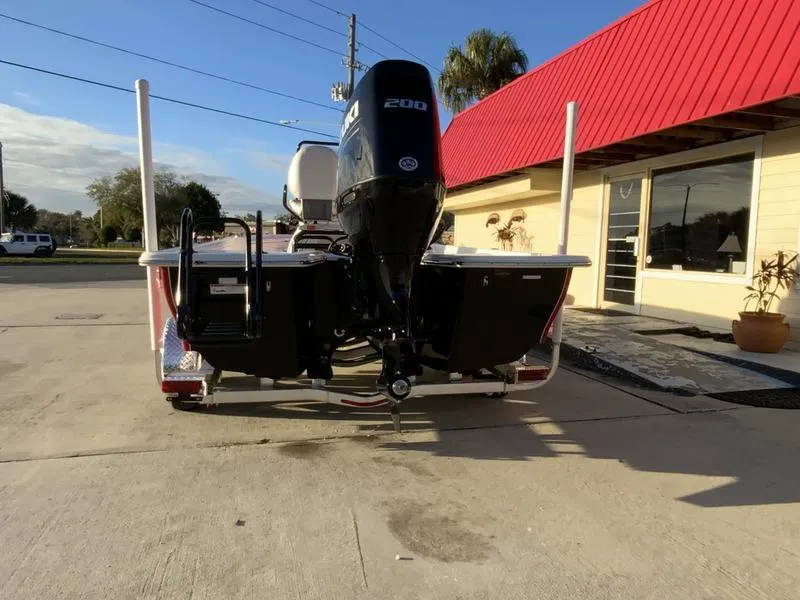 Slide: The Image of 2022 Blue Wave 2200 STL boat on trailer at dealership, palm tree in background. - 2