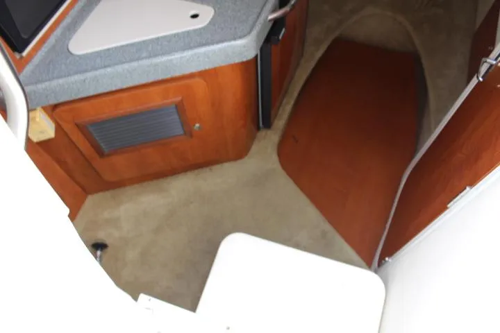 Slide: The Image of Interior cabin of a 2005 Larson Cabrio 240 boat with kitchenette and carpeted floor. - 14