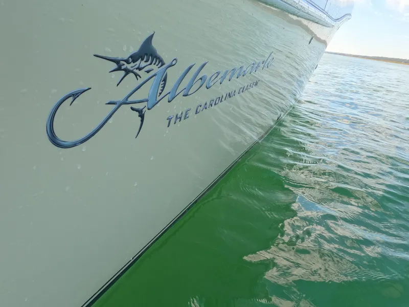 Slide: The Image of 2022 Albemarle 27 DC boat deck with teak flooring and engine hoses, docked on green water. - 24