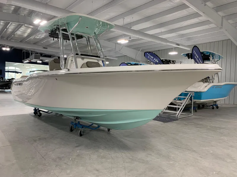 Slide: The Image of 2024 Key West 239 FS boat in showroom, white and teal color scheme. - 2