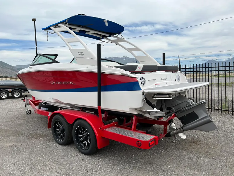 Slide: The Image of 2022 Regal LS2 Surf boat on a red trailer, parked outdoors. - 1