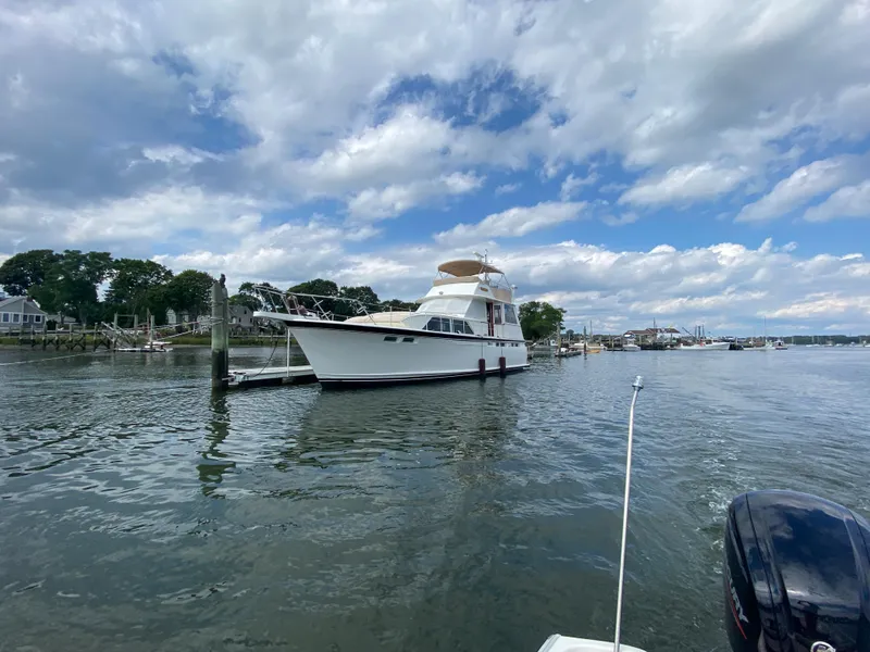 Slide: The Image of 1973 Chris-Craft 47 Commander Flush Deck yacht docked in a serene marina. - 2