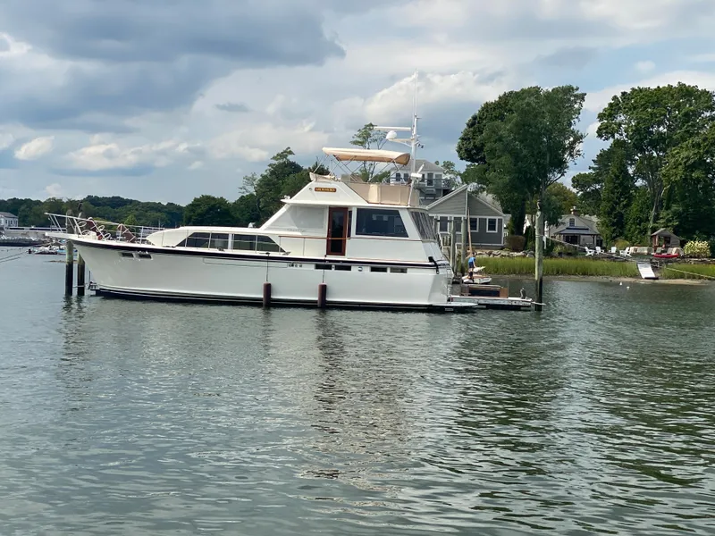 Slide: The Image of 1973 Chris-Craft 47 Commander Flush Deck yacht docked on a serene lake. - 3
