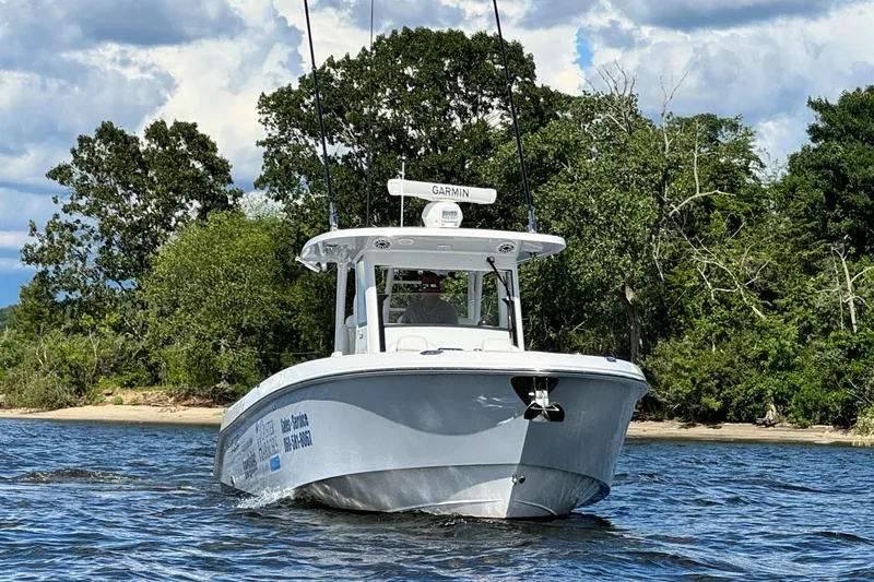 Slide: The Image of 2023 Everglades 335 Center Console boat cruising on a lake near a forested shoreline. - 0