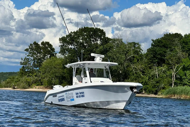 Slide: The Image of 2023 Everglades 335 Center Console boat cruising on a lake with a forested shoreline. - 1