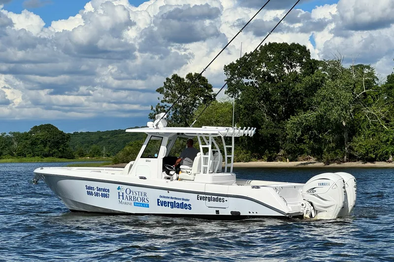 Slide: The Image of 2023 Everglades 335 Center Console boat cruising on a lake with lush green trees in the background. - 3
