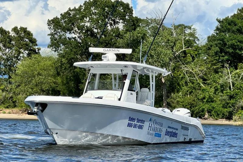 Slide: The Image of 2023 Everglades 335 Center Console boat on water with lush green background. - 6