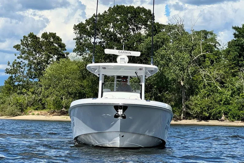 Slide: The Image of 2023 Everglades 335 Center Console boat on water near a forested shoreline. - 7