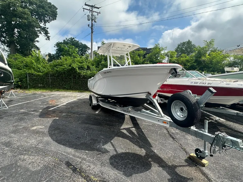 Slide: The Image of 2022 Sea Fox 248 Commander boat on trailer in parking lot, surrounded by greenery. - 3