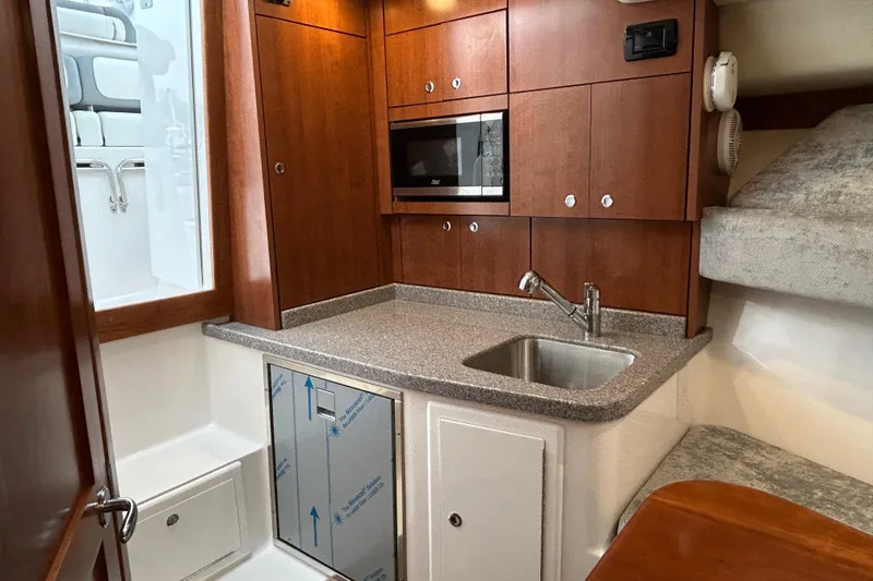 Slide: The Image of 2024 Albemarle 30 Express boat interior with kitchenette, featuring wood cabinets and stainless steel sink. - 15
