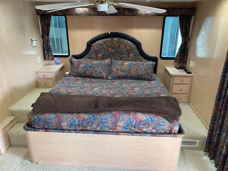 Slide: The Image of Sumerset 86' by 18' 1998 houseboat bedroom with floral bedding and wooden furniture. - 9