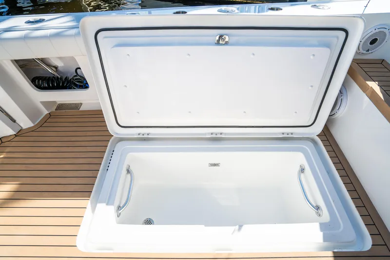 Slide: The Image of Henriques 50 Sportfisherman 2025 open storage compartment on teak deck. - 18