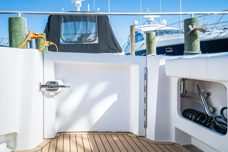 Slide: The Image of Henriques 50 Sportfisherman 2025 boat deck with teak flooring and docked yachts. - 20