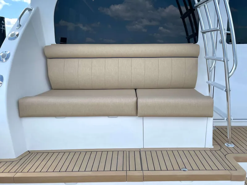 Slide: The Image of Henriques 50 Sportfisherman 2025, beige cushioned bench seat on teak deck. - 22