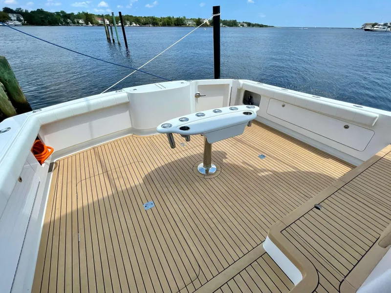 Slide: The Image of Henriques 50 Sportfisherman 2025 boat deck with rod holders, docked by the water. - 23