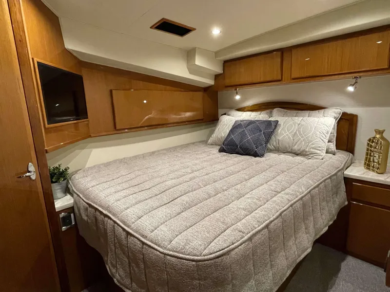 Slide: The Image of 2025 Henriques 50 Sportfisherman cabin with a cozy bed, wooden cabinets, and modern lighting. - 31