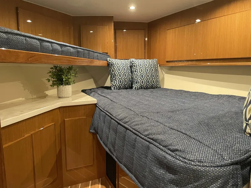 Slide: The Image of Henriques 50 Sportfisherman 2025 cabin with blue bedding and wooden cabinetry. - 33