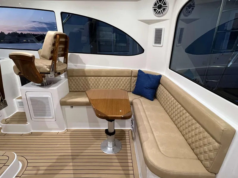 Slide: The Image of 2025 Henriques 42 Express boat interior with beige seating, wooden table, and captain's chair. - 11