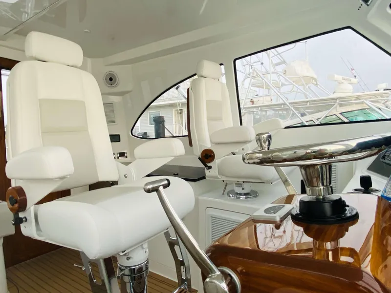 Slide: The Image of 2025 Henriques 42 EXHTB helm station with white captain chairs and wooden steering wheel. - 19