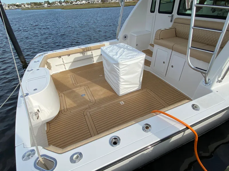 Slide: The Image of Henriques 42 EXHTB 2025 model boat deck with seating and storage, docked by the water. - 7