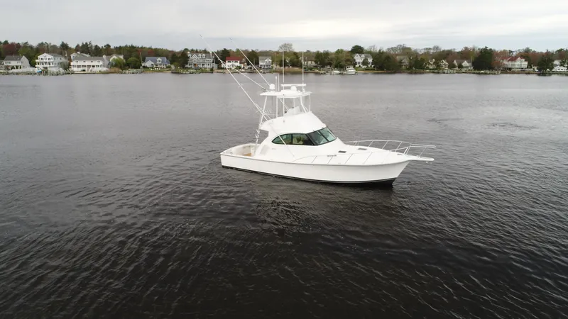 Slide: The Image of 2025 Henriques 42 EXHTB boat on calm water near residential shoreline. - 4
