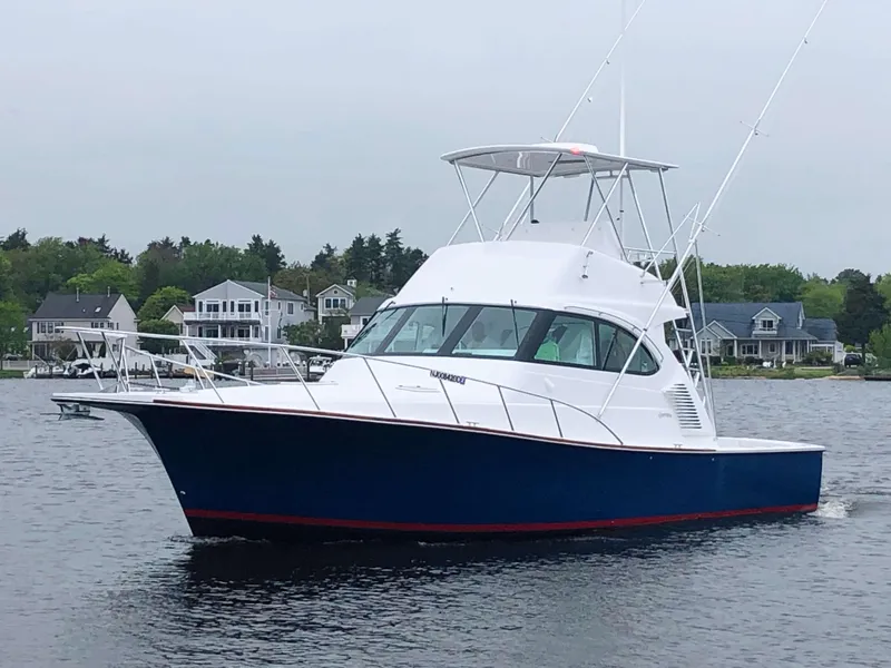 Slide: The Image of 2025 Henriques 42 EXHTB boat cruising on a calm lake near waterfront homes. - 5