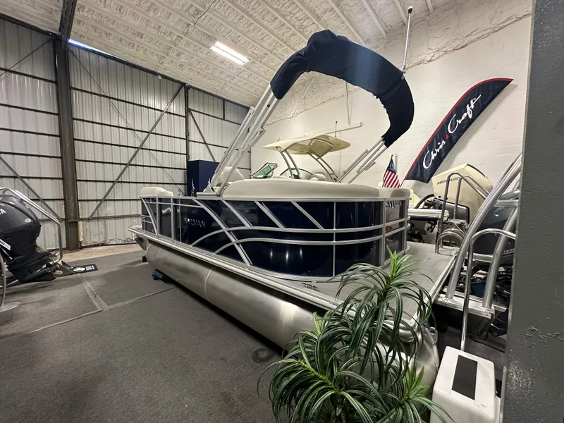 Slide: The Image of 2026 Sylvan Mirage 8520 LZ pontoon boat in showroom, featuring sleek design and canopy. - 2